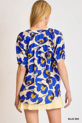 Woman wearing a blue floral patterned top on a plain background